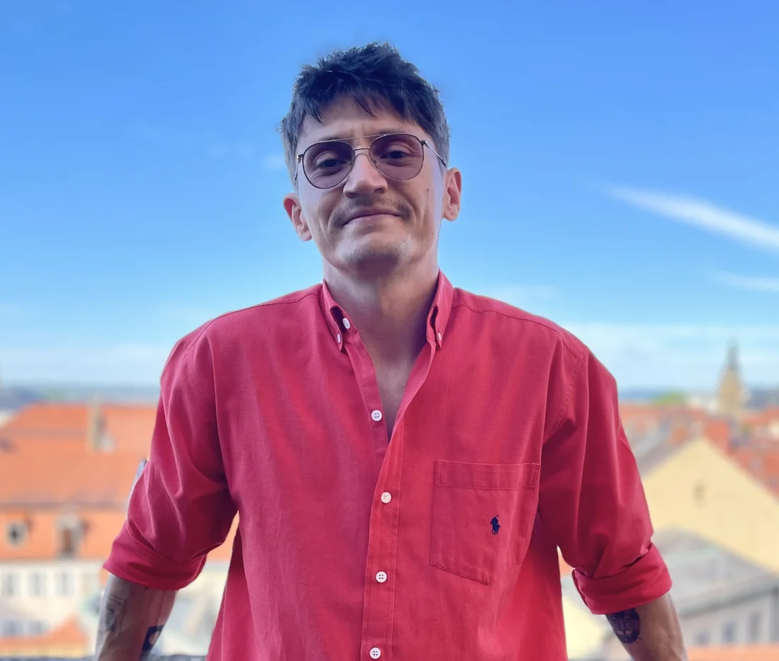 Marius Bontas smiling on a balcony above red rooftops